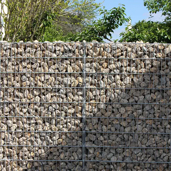 Stabile Gabionenwand aus Natursteinen, geeignet als Sichtschutz oder Hangabstützung in modernen Gärten.