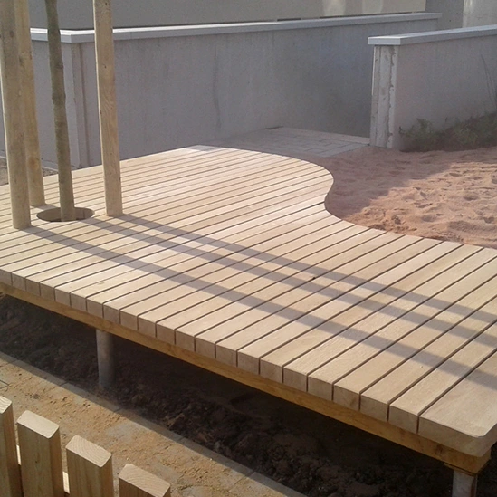 Holzplattform mit geschwungenem Design, Teil eines Spielplatzes, unterstützt von stabilen Holzpfosten.